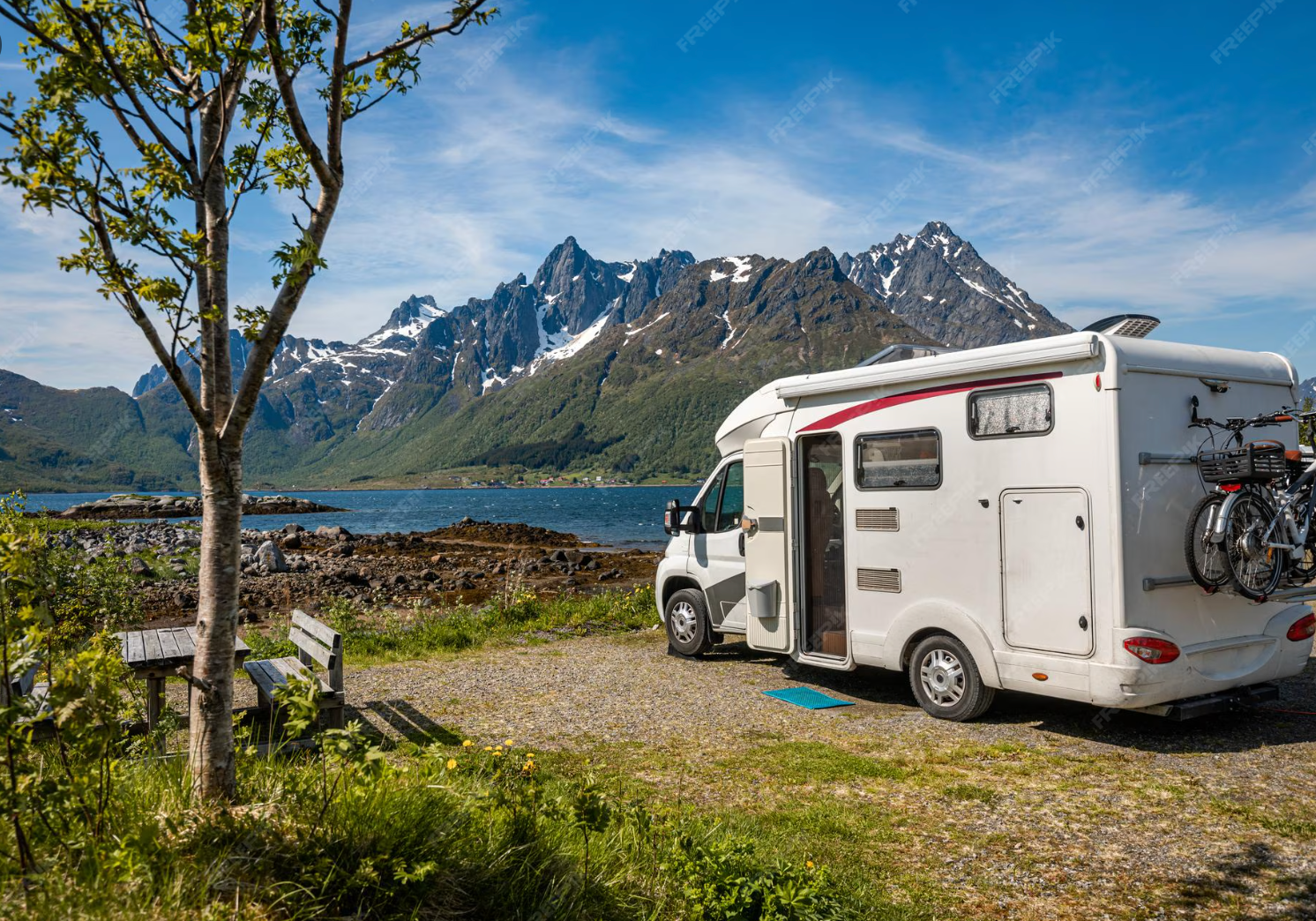 Camping-car en pleine nature au bord d’un lac avec vue sur les montagnes